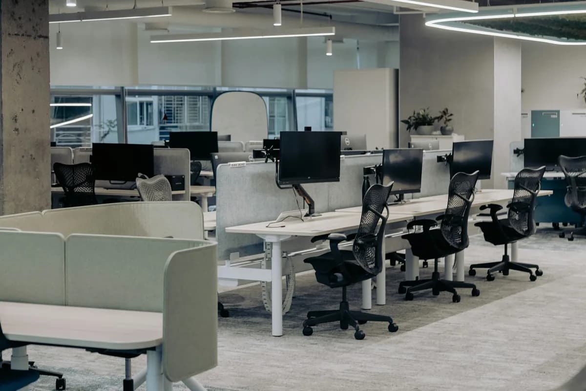 Open-plan office with desks, monitors and linear lighting