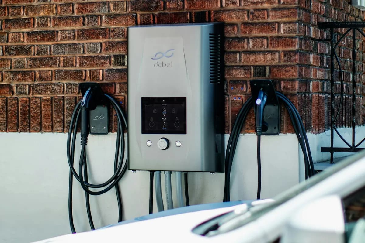 Wall-mounted EV charger on a red brick wall beside a parked car